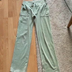 Mintgröna mjukisbyxor Juicy Couture S - Supermjuka mintgröna mjukisbyxor från Juicy Couture med bred resår i midjan, stora fickor fram och bak samt broderad JC-logga. Byxorna har raka ben och är gjorda i velour. 