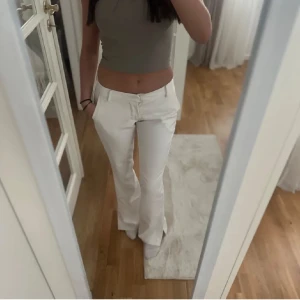 Vita bootcut kostymbyxor från BikBok - Snygga vita kostymbyxor från BikBok i storlek 36. Byxorna har bootcut-modell, låg midja och klassiska fickor. Perfekta för en clean och fräsch look. Materialet är mjukt och följsamt med dragkedja och knapp framtill.