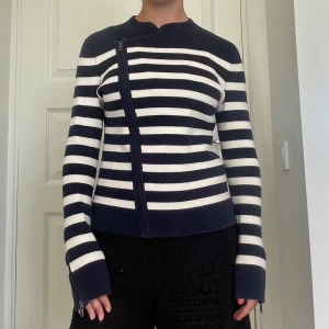 Randig kofta från Gap med dragkedja - Säljer en snygg stickad kofta från Gap i marinblått och vitt med horisontella ränder. Koftan har en cool asymmetrisk dragkedja framtill, ribbade axelpartier och långa ärmar med dragkedjedetalj vid ärmslut. Perfekt för dig som gillar en stilren men ändå unik look. Skriv om du undrar något, kolla min profil innan du trycker på köp nu💕💕