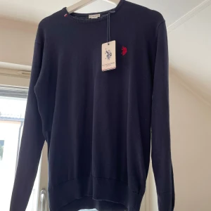 Oanvänd stickad US Polo Assn. tröja - Oanvänd blå stickad tröja. Nypris ca 500kr. Pris 350kr eller bud