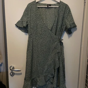 Plus size wrap-klänning  - Grön PLUS SIZE wrap-klänning med vita prickar. 
