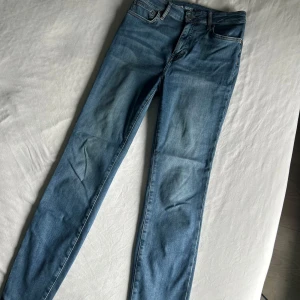 Blå high waist skinny jeans M - Snygga blå skinny jeans med high waist och klassisk femficksdesign. Jeansen har en smal passform och är tillverkade i stretchigt denim för en bekväm känsla. Perfekta för dig som gillar en tight siluett och vill ha ett par stilrena vardagsjeans.