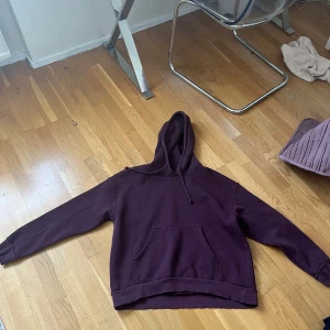 Vinröd  hoodie från Pull&Bear - Säljer en vinröd hoodie från Pull&Bear i storlek M. Tröjan har huva med snörning, magficka och långa ärmar. Tillverkad i mjuk bomullsmix, perfekt för chill dagar eller när du vill ha en enkel och snygg look.