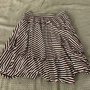 Randig volangkjol från Olars Ulla - Superfin kortkjol från Olars Ulla med svartvita ränder, elastisk midja och volanger. Storleken står tyvärr inte men skulle gissa på M/L