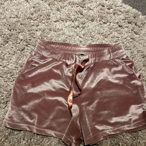 Rosa sammets-shorts från NLY One - Supermjuka och glansiga rosa shorts i sammet från NLY One. De har en bekväm midja med snörning i satin och en loose passform. Perfekta för chill dagar eller när du vill känna dig extra comfy och stylish.
