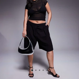 Svarta bermudashorts i linnelook - Stilrena svarta bermudashorts med lös passform och midwaist. Klassisk design med hällor för bälte, fickor i sidorna och bakfickor. Nyskick - aldrig använda!