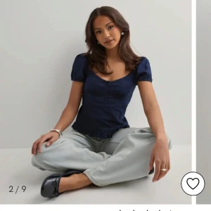 Mörkblå blus med puffärm och knappar - Supersöt mörkblå blus med korta puffärmar, v-ringning och små knappar framtill. Blusen har en lätt rynkad effekt vid bysten och volangkant nertill. Perfekt att styla med jeans för en chill look .