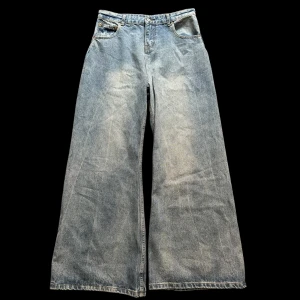 Flared Jeans ”Margiela” - Säljer ett par ljusblå jeans med riktigt breda ben och hög midja. De har klassisk femficksdesign och är tillverkade i jeansmaterial. Perfekta för dig som gillar en avslappnad och trendig look.