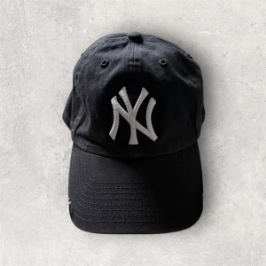 Svart Yankees keps från 47 Brand - Svart New York Yankees keps från 47 Brand med broderad vit NY-logga framtill och Yankees-text under skärmen. Klassisk böjd skärm och avslappnad passform. Tillverkad i 100% bomull för en skön känsla och snygg look.