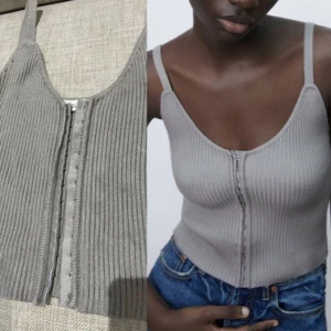 Grå ribbad linnetopp från Zara - Säljer en grå ribbad topp från Zara med smala axelband och snygg v-ringning. Toppen har croppad passform och knäppning framtill med små hakar. 