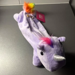 Lila enhörningspenskrin från Sense - Supergullig lila pennskrin i form av en enhörning med silvrigt horn, regnbågsfärgad svans och rosa man. 📩 Skicka gärna ett meddelande vid frågor eller om du vill ha flera bilder! 🌸😊 📦 Jag skickar snabbt och packar alltid med omsorg!