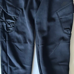Nike Tech Byxor - Äkta Nike Tech byxor. Aldrig använt de enbart testat och upptäckte då att de var förstora så säljer de på grund av det. Nypris ca 1200kr