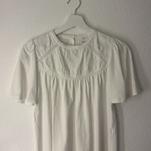 Vit broderad T-shirt från Zara - Supersöt vit tshirt från Zara med broderade detaljer upptill och korta ärmar. Lätt och luftig modell med rund halsringning och fina sömmar. I storlek 164.
