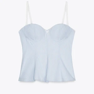 Ljusblå randig korsettopp med rosett - Supersöt ljusblå korsettopp med tunna axelband och diskreta vita ränder. Toppen har formade kupor och en liten rosett framtill, samt en lätt utsvängd nederdel som ger en feminin siluett. Perfekt för dig som vill ha en chic och trendig look.