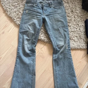 Hollister  bootcut jeans ljusblå - Ljusblå Hollister jeans med bootcut passform och klassiska fem fickor. Jeansen har låg midja och slitna detaljer vid fickor och benslut för en cool, avslappnad vibe. Tillverkade i klassiskt denimtyg som sitter snyggt på kroppen.