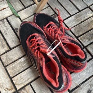 Svarta och röda sneakers från Saucony - Snygga sneakers från Saucony i svart mesh med röda och silverfärgade detaljer. Skorna har röda snören, vadderad plös och sula i rött. Perfekta för dig som gillar sportig stil och vill ha bekväma skor till vardagen.