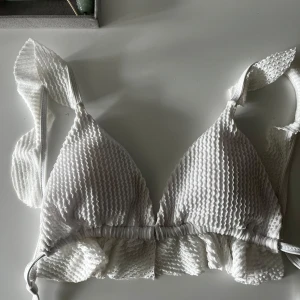 Vit triangelbikini med volang - Vit bikiniöverdel Storlek: S  Köpt: i Spanien förra året  Defekt: fläck på insidan (syns inte när man bär den på) se bild 2!