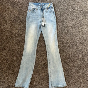 Ljusblå bootcut jeans Capri Collection - Ljusblå jeans från Capri Collection med bootcut passform och snygga slitningar. Klassisk femficksmodell med dragkedjedetalj framtill och stjärnknapp. Jeansen är i mjuk denim och har en bekväm midja. Köpte i helgen, helt nytt skick, har inte används, säljer pga att de inte riktigt är min stil. 