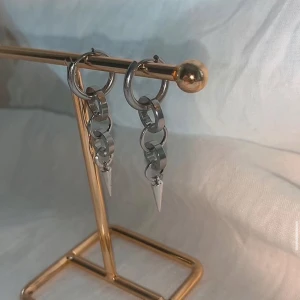 Silvriga örhängen med kedjor och spikes - Coola silvriga örhängen med ringar i kedje-design och spetsiga spikes längst ner. Ger en edgy vibe och passar perfekt om du gillar statement-smycken. Metallisk finish och modern look.