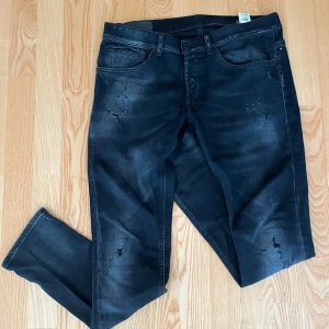 Dondup George W33 svart slitningar - Dondup George. Snygga svarta jeans med slitna detaljer och tvättad look. Modellen är slim och har klassiska fem fickor samt dragkedjegylf. Jeansen har en modern, något smal passform och är tillverkade i stretchig denim för extra komfort.