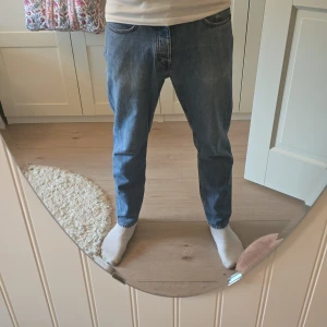 Tiger of Sweden Jeans - Tiger of Sweden i ljusblå denim med raka ben och normal passform. Byxorna har fem fickor, knappgylf och snygga kontrastsömmar. Perfekta för en avslappnad och tidlös look. Ikonisk läderpatch bak i midjan. Storlek 31/36"