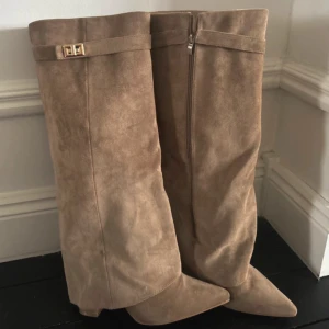 Beige mockastövlar med spetsig tå - Snygga beige höga stövlar i mocka med spetsig tå och låg klack. Köpta på raglady för 1000