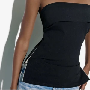 ZARA Svart topp - Snygg svart tubtopp med en dragkedjedetalj längs sidorna. Köpt från Sellpy, prislappen sitter kvar. Säljer för att den tyvär är för liten för mig.