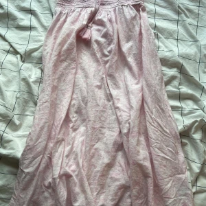 Ljusrosa långkjol från Gina Tricot - Supersöt ljusrosa långkjol från Gina Tricot med smock i midjan och dekorativ knytning med tofs. Säljer den för att den är lite för kort