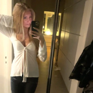 Design by si tröja - Säljer en vit långärmad omlottopp med djup v-ringning och snygg knytning framtill. Jättebra kondition! Storlek xs/s🥰Gärna diskutera om pris!