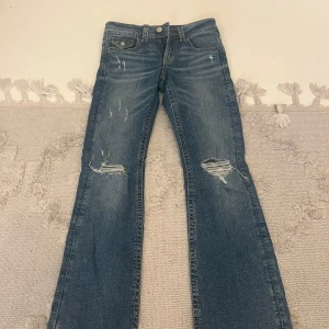Blå bootcut jeans från Gina Tricot - blå jeans från Gina Tricot i bootcut-modell med slitna detaljer och hål på knäna. Helt oanvänd i storlek 152 säljer för 290kr men priset kan förhandlas. Säljs pga för liten storlek 🥰 ord pris: 359kr 