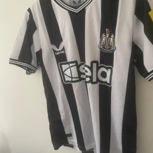 Newcastle United randig fotbollströja S - Säljer en officiell Newcastle United fotbollströja från Castore i storlek S. Tröjan har klassiska svarta och vita vertikala ränder, klubbmärke på bröstet och sponsortryck. Tillverkad i lätt och ventilerande material, perfekt för match eller träning eller till en drop!!❤️