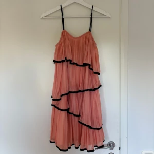 Rosa volangklänning med svarta detaljer - Superfin rosa långklänning med flera lager volanger och svarta kanter. Köpt i Frankrike 💞