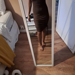 Brun ribbad kortklänning med snörning - Säljer en tight brun kortklänning med ribbad struktur och snörning på sidan. Klänningen har korta ärmar och en kroppsnära passform som framhäver figuren. Perfekt för dig som gillar en enkel men ändå snygg stil.