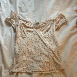 Blommig topp - Supersöt blommig topp från Nelly. Går att ha vanligt och off-shoulder🥰Vit med blommor på💐
