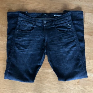 Replay Anbass svarta slim jeans 31/32 - Snygga svarta Replay Anbass jeans i slim fit med klassisk femficksdesign och diskreta slitningar framtill med storlek 31/32. Jeansen har dragkedjegylf och är tillverkade i stretchig denim för en bekväm passform. Perfekta för dig som gillar en stilren look. Tveka inte med att ställa frågor.