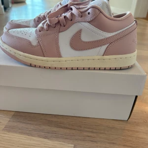 Nike Air Jordan 1 Low rosa/vit - Nike Air Jordan 1 Low i en snygg kombo av ljusrosa och vitt skinn. Storlek 38 helt ny