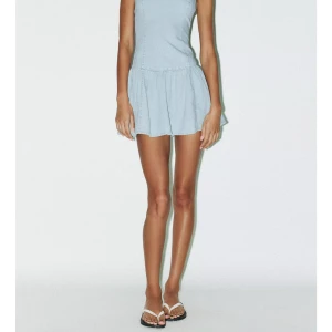 Ljusblå axelbandslös jeansklänning - Superfin ljusblå kort klänning i jeansmaterial med axelbandslös design och volangig kjol. Sitter snyggt och har en clean look som är lätt att styla med sneakers eller sandaler. Helt slutsåld i nästan alla storlekar!