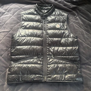 Svart dunväst från Moncler - Snygg Moncler Gui I fantastiskt skick i material mm! Tyvärr har löparna från dragkedjan fastnat och går inte att öppna helt, därav det billiga priset. Moncler storlek 3. Hör gärna av er vid frågor och funderingar MVH Lavish!☺️