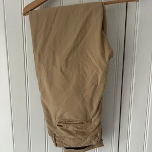 Beiga chinos med fickdetalj - Snygga beiga Incotex chinos med klassisk passform och bakficka med knapp. Perfekta för en clean och stilren look. Tillverkade i mjukt bomullstyg som känns skönt mot huden. Ny pris över 2000