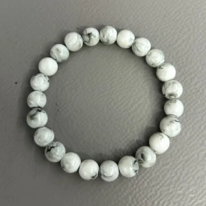 Stilrent vitt pärlarmband - Stilrent armband med runda vita pärlor och grå marmorerade detaljer. Elastiskt band gör det enkelt att ta på och av. Perfekt accessoar för dig som gillar minimalistisk och fräsch stil. Passar 15-17 cm handled, kan justera så d blir större också.