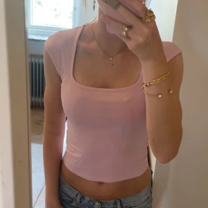 Ljusrosa croppad topp Gina Tricot - Superfin ljusrosa croppad topp från Gina Tricot med fyrkantig ringning och korta ärmar. Tunn och mjuk i bomullsmix, perfekt till jeans eller kjol. Enkel och stilren design som känns fräsch och trendig.