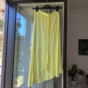 Gul långkjol från & Other Stories - Säljer en ljusgul långkjol från & Other Stories Stockholm Atelier. Dragkedja i sidan för enkel påklädning. Perfekt för sommarens alla tillfällen!