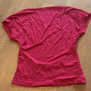 Rosa kortärmad topp med öppen rygg - Säljer en snygg rosa topp i bomull med korta ärmar och en cool öppen rygg. Modellen är figurnära och passar perfekt till jeans eller kjol. Enkel men ändå unik med sin öppna ryggdetalj. Perfekt för dig som vill sticka ut lite extra!