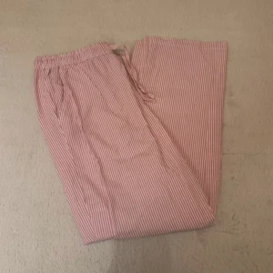 Randiga vit rosa pyjamasbyxor med snörning - Säljer ett par vit rosa randiga pyjamasbyxor med elastisk midja med snörning. Byxorna är raka i modellen och lätta och luftiga!🩷