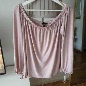 Ljusrosa offshoulder blus från Amisu - Superfin ljusrosa blus från Amisu med offshoulder-modell och långa ärmar. Blusen har resår vid halsringningen och ärmsluten samt söta knytband vid handlederna. 