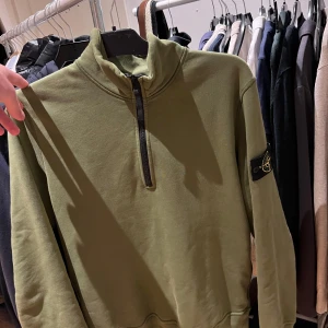 Half zip tröja Stone Island - Säljer en långärmad tröja från Stone Island med klassisk patch på ärmen. Tröjan har en hög krage och half zip-dragkedja framtill. Tillverkad i mjuk bomull och har en clean, stilren look som passar perfekt till mesta. Toppskick typ aldrig använd