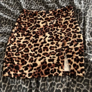 Leopardmönstrad kortkjol - Snygg kortkjol med leopardmönster i beige, brunt och svart. Kjolen har en rak passform och en liten slits framtill för lite extra.