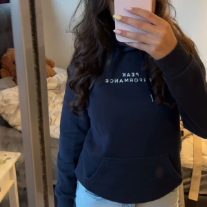 Mörkblå hoodie från Peak Performance - Säljer en mörkblå hoodie från Peak Performance med vit logga på bröstet. 