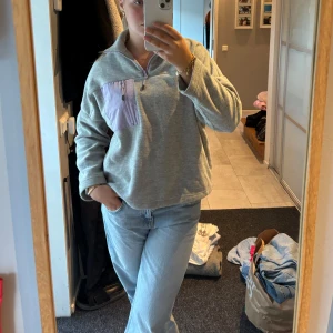 Grå half zip - Mysig grå fleece med lila bröstficka och dragkedja. Perfekt till afterski eller bara när man vill chilla. Är i XS men skulle säga att den är mer S/M