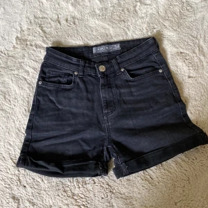Svarta jeansshorts från Amisu - Svarta jeansshorts från Amisu med klassisk femficksdesign och uppvikta benslut. Modellen är högmidjad och har knapp- och dragkedjestängning framtill. Perfekta för en chill sommardag och lätta att matcha med allt. 💕👌🏼